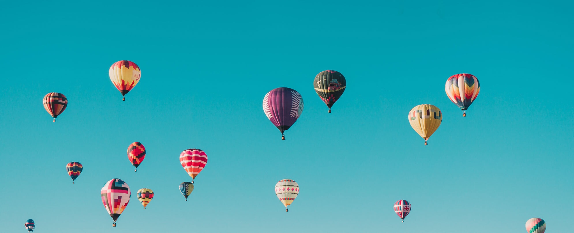 Bright blue sky with different color hot air balloons
